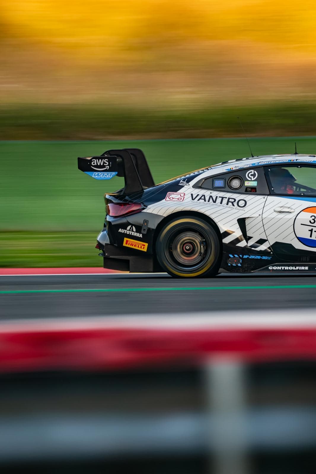 Trois quarts arrière d'une voiture de course blanche à grand aileron sur la piste
