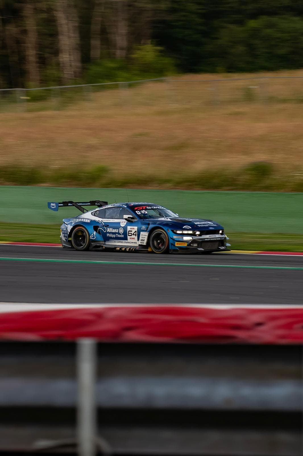 Voiture de course bleue saisie en filé le long des vibreurs rouges et blancs