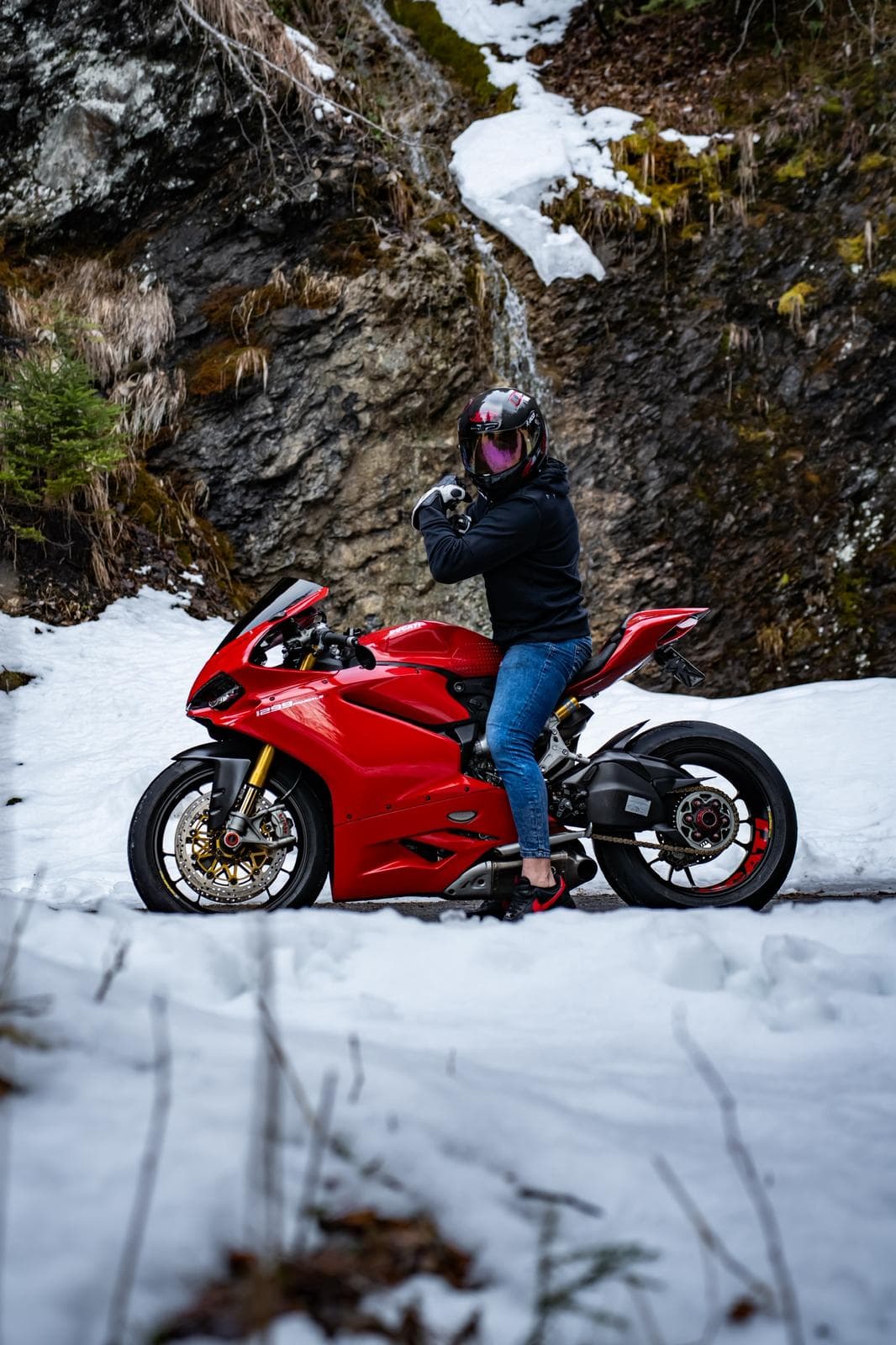 Moto Ducati Panigale rouge à l'arrêt devant une cascade en montagne